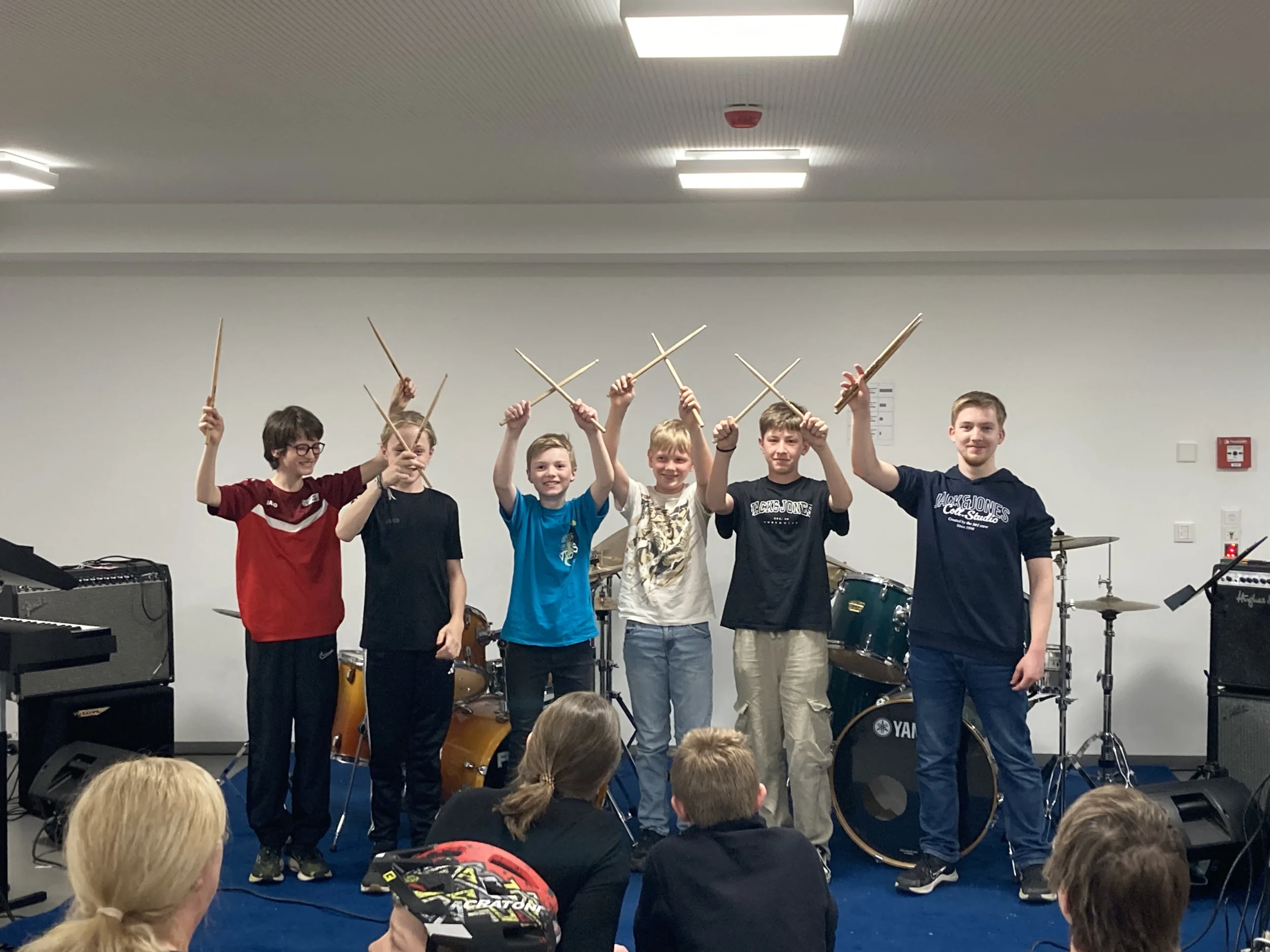 Sechs junge Schlagzeuger vor dem Drum-Set, zeigen ihre Schlagstöcke